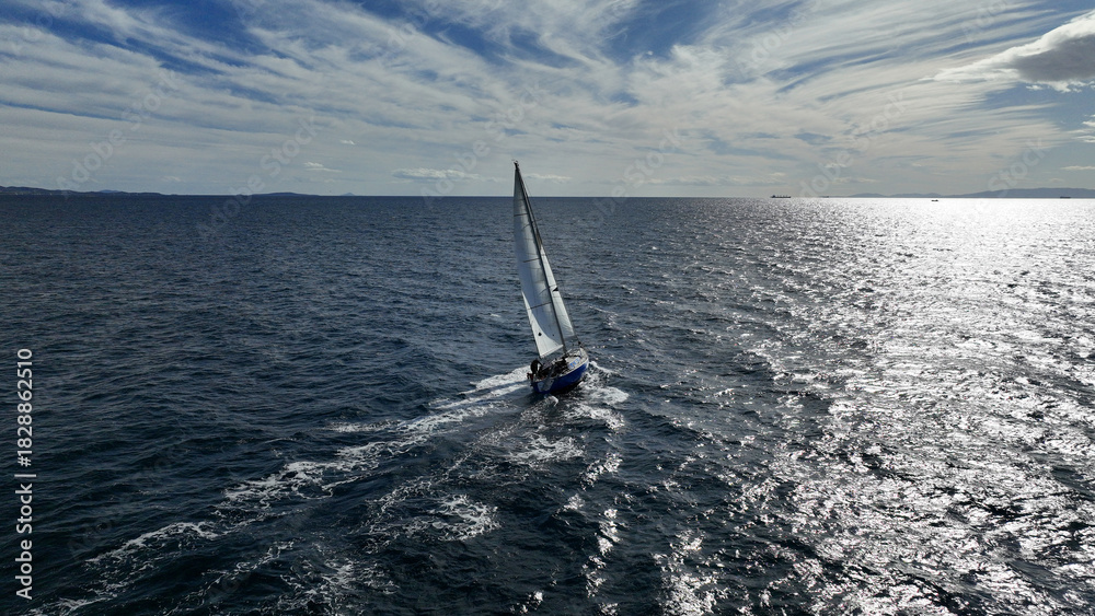 Naklejka premium Aerial drone photo of beautiful sail boat with white sails cruising deep blue waves in Aegean sea