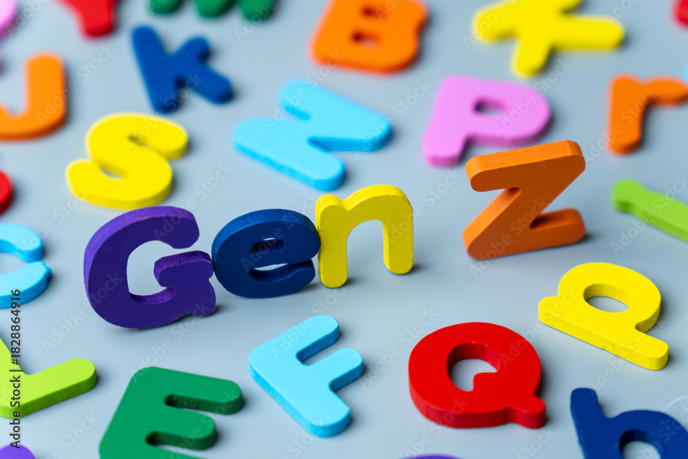 Naklejka premium The phrase GEN Z is spelled out in colorful wooden letters scattered on a gray background. Modern generation, digital natives, youth culture, demographics, and future trends concept.
