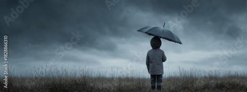 Young figure holding black umbrella under impending gloomy sky observing dark clouds on an overcast day