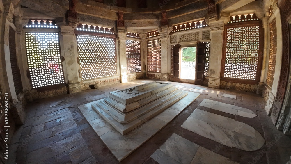 Fototapeta premium Interior View of the Tomb of Imam Zamin, Highlighting the Central Marble Cenotaph and the Intricate Geometric (Lattice) Windows that Filter Sunlight onto the Floor and Walls of the Modest Chamber