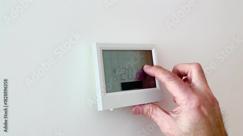 close-up of a finger raising the temperature from 18 to 20 degrees Celsius on the touchscreen of a heating thermostat, setting the comfortable temperature in the home in winter