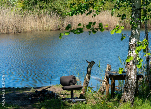 Serene summer view of a pond with a chair and table on the shore