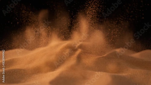 Abstract eruption of fine orange particles, resembling dynamic desert dust or sand, creating a textured, cloud-like explosion against a deep black background, showcasing energetic motion