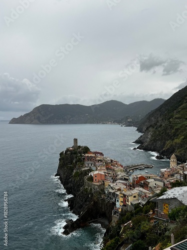 Dramatic High-Angle View of Vernazza Village, Cinque Terre, Italy, Clinging to the Rugged Coastline with Doria Castle Tower under a Gray and Cloudy Sky