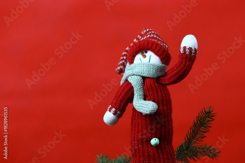 Cozy handmade snowman decoration in warm Christmas atmosphere with spruce branches and red holiday background