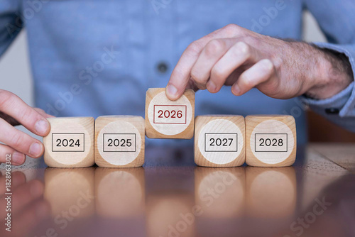 Focused on year 2026. Business planning and strategy in new year. Performance and highlight concept. Holding the wooden cubes with number 2026 on grey background. Start of year concept. 2026 banner.