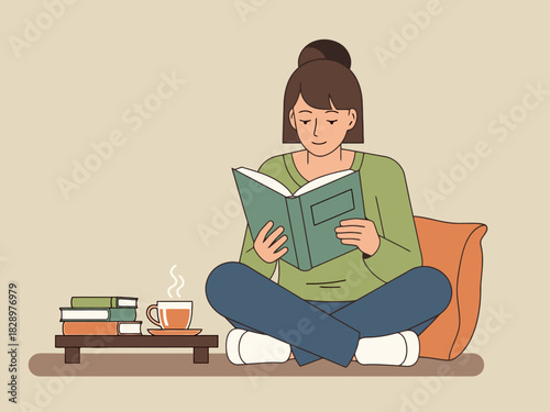 A smiling woman enjoying a good book while sitting cross-legged next to a hot drink.