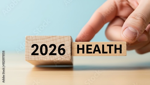 Hand placing wooden block with word health next to block with year 2026 symbolizing future healthcare planning or goal setting