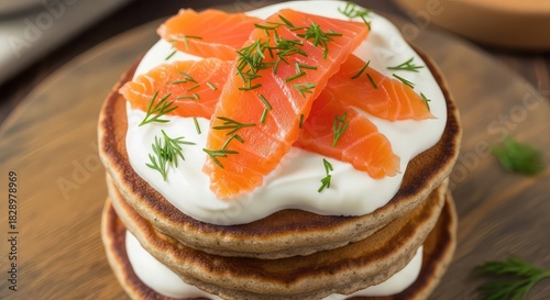 Delicious stack of pancakes with cream cheese, salmon and dill on wooden board