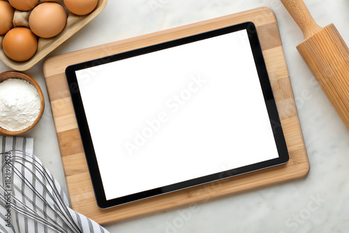 Digital tablet on cutting board with baking ingredients overhead view