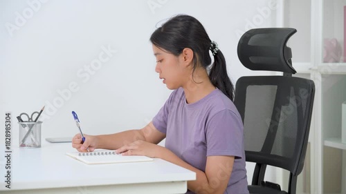A cheerful woman sits at her desk with a laptop, ready to work or study from home