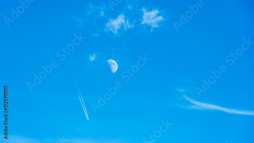 Luna creciente foto diurna al atardecer con nubes blancas y estela de avión