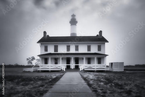 The keeper's quarters building with the Bodie Island Lighthouse in the background in black and white in Nags Head, North Carolina
