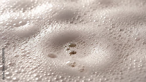 Close Up Macro Shot of White Soap Suds Bubbles and Foam Texture with Light Reflections in a Creamy Background Subtle Ripples and Smooth Surface in Natural Light