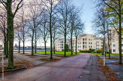 Amsterdam, The Netherlands, November 25, 2025: white plastered urban villas at IJplein neighbourhood, with the Central Station and the IJ river in the background