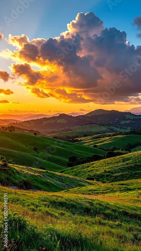 Golden Hour Sunset Over Rolling Green Hills With Dramatic Clouds and Rays of Light Shining Through