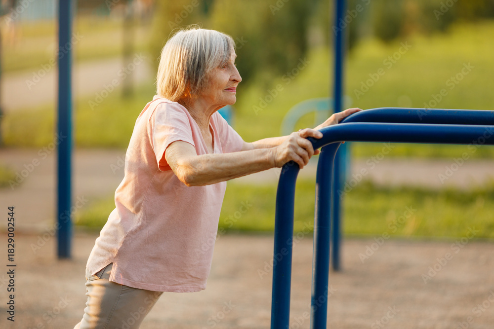 Obraz premium Elderly Woman Doing Incline Push-Ups Outdoors. Physical Activity for Seniors.