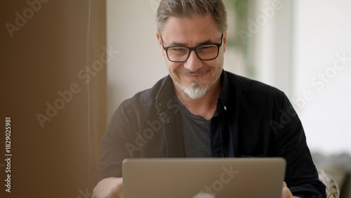 Businessman in home office. Middle aged man working with laptop computer at home outdoor on terrace. Online work, happy, smiling.