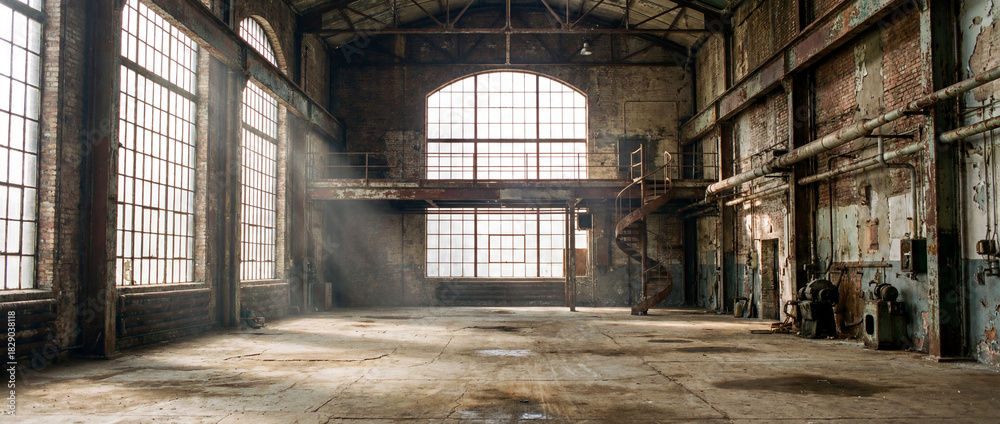 Fototapeta premium Abandoned industrial warehouse with natural light and dust 