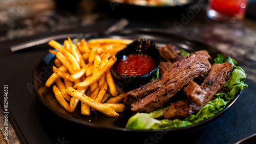 Carne asada servida con papas fritas y salsa en restaurante nocturno