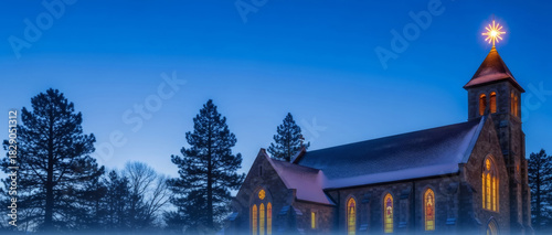 Historic stone church with glowing stained glass windows and a Bethlehem star on its spire, illuminated at night during the Christmas season for holiday designs. Banner with copy space