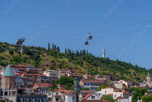 Fotografie Hillside cityscape with cable cars and statue under clear blue sky
