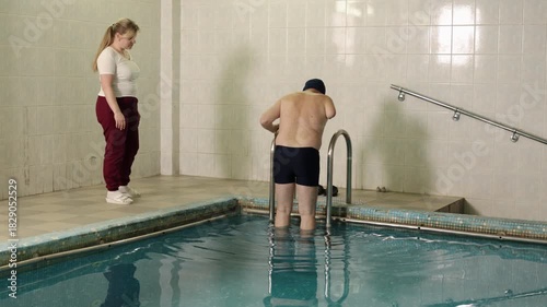 hydrotherapy session, supportive atmosphere, patient care. Under supervision of medical professional, man with physical disability prepares for hydrotherapy session.