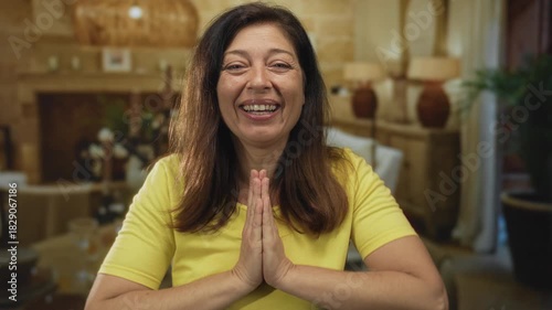 Wallpaper Mural Middle age woman smiles and presses palms together by fireplace in cozy living room; gratitude kindness. Torontodigital.ca