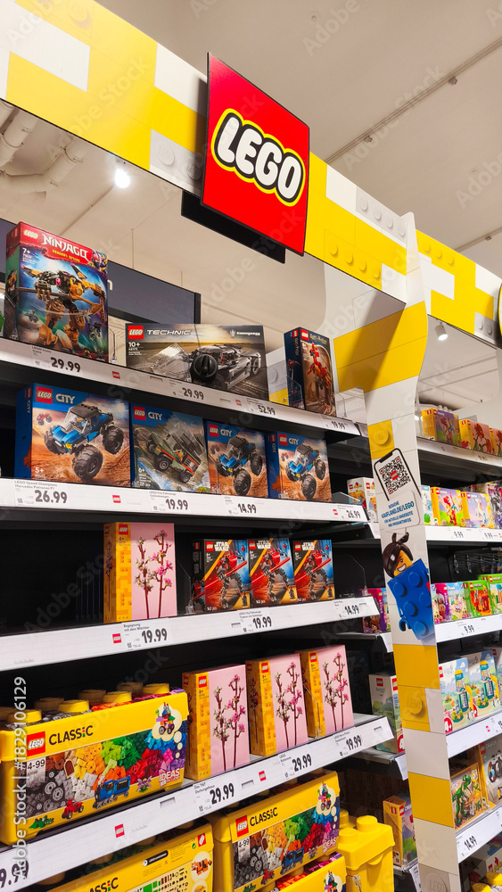 Naklejka premium Potsdam, Germany - October 21, 2025: LEGO toy display in a retail store showcasing various colorful building sets and creative play options for children and enthusiasts