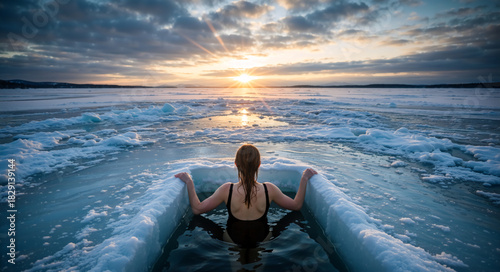 Woman from behind taking a polar plunge in a frozen lake at sunset. Cold water immersion for wellness and resilience