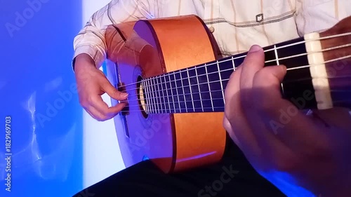 Practicing rumba flamenco with acoustic guitar in blue room at night