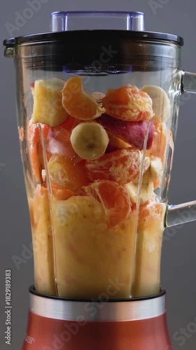 Making a healthy fruit smoothie with fresh bananas, oranges, and berries in a blender
