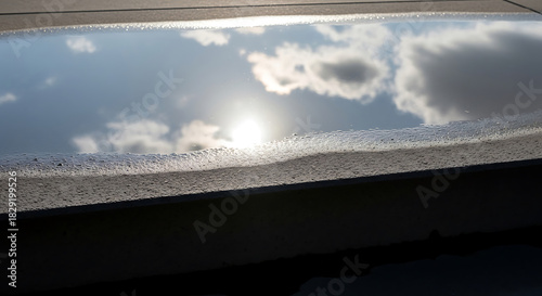 Cloud Reflection in Water Puddle on Flat Roof After Rain Storm Showing Sky Serenity