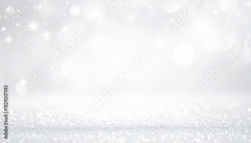 A close-up perspective of a sparkling silver glitter surface fading into a soft, defocused grey background with bokeh lights. 