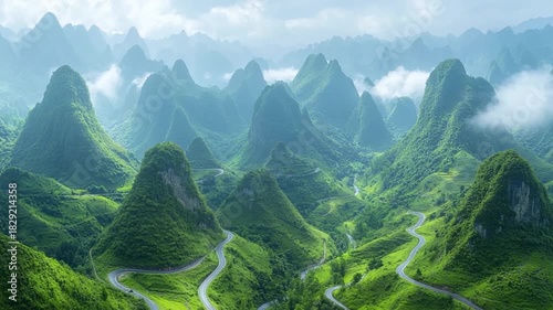 A winding road snakes through a lush landscape of conical mountains, bathed in soft light.