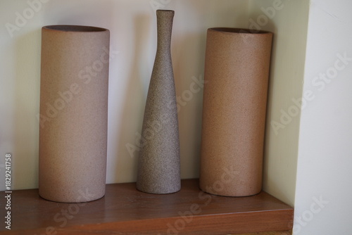 Minimalist ceramic vases in natural tones arranged on a wooden shelf, showcasing simple shapes and textures for stylish home decor accents