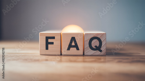 Wooden blocks spelling faq on a wooden surface with a blurred background representing frequently asked questions and information resources for users online and offline