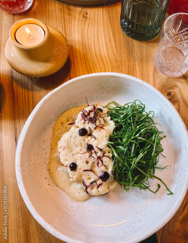 Delicious plate of food featuring fresh herbs and creamy sauce served on a wooden table