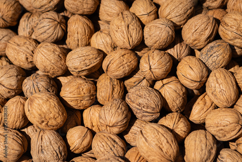 Unshelled walnuts densely packed with rough texture and natural brown tones