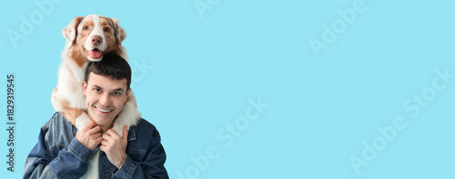 Young man with Australian Shepherd dog hugging on blue background, closeup