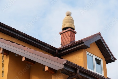 Winter Humor: Knitted Hat Perched on Brick Chimney