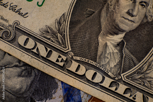 Close-up view of one dollar bill showing George Washington and fine details of currency design in warm lighting
