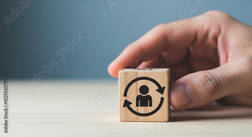 Hand holding wooden block with rotating person icon symbolizing employee turnover talent management or career change concept