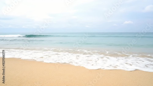 Golden Sand Beach With Gentle Ocean Waves Under A Cloudy Sky