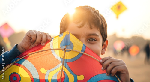 Smiling Boy Hiding Behind Colorful Kite at Sunset Outdoors