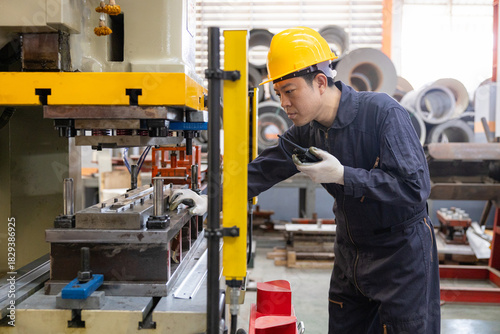 Industrial worker inspecting machinery with walkie-talkie