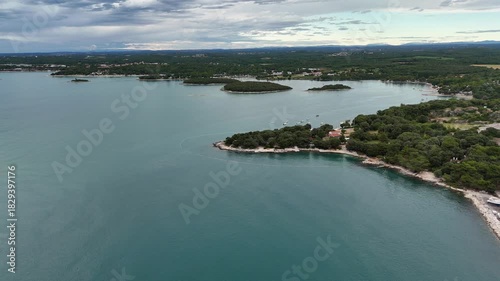 Drone captures a stunning coastal bay with small islands surrounded by bright turquoise water. Shot in Slovenia near the Adriatic coastline, highlighting natural coastal beauty.