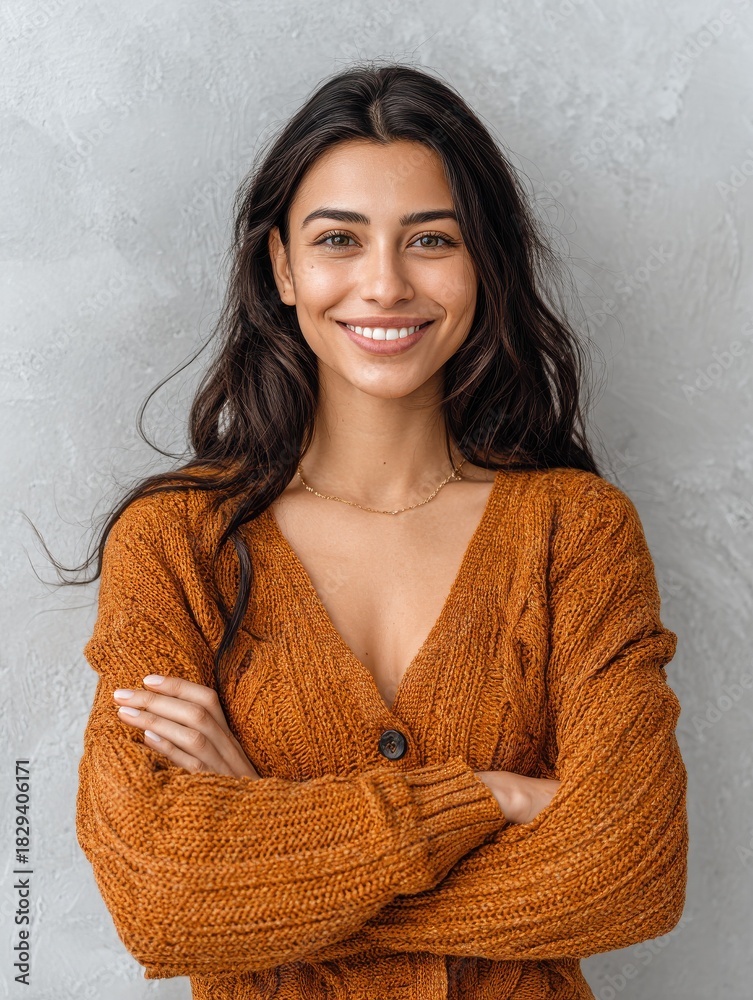 Obraz premium portrait of a young latin woman with pleasant smile and crossed arms isolated on grey wall with copy space beautiful girl with folded arms looking at camera against grey wall cheerful hispanic woman 