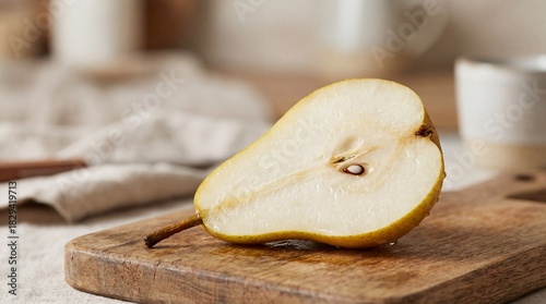 Freshly cut pear half resting on a wooden cutting board with a rustic kitchen background