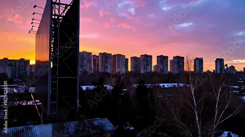 Vibrant Sunset Over Apartment Buildings With Billboard Silhouetted Against Orange And Purple Sky During Dusk